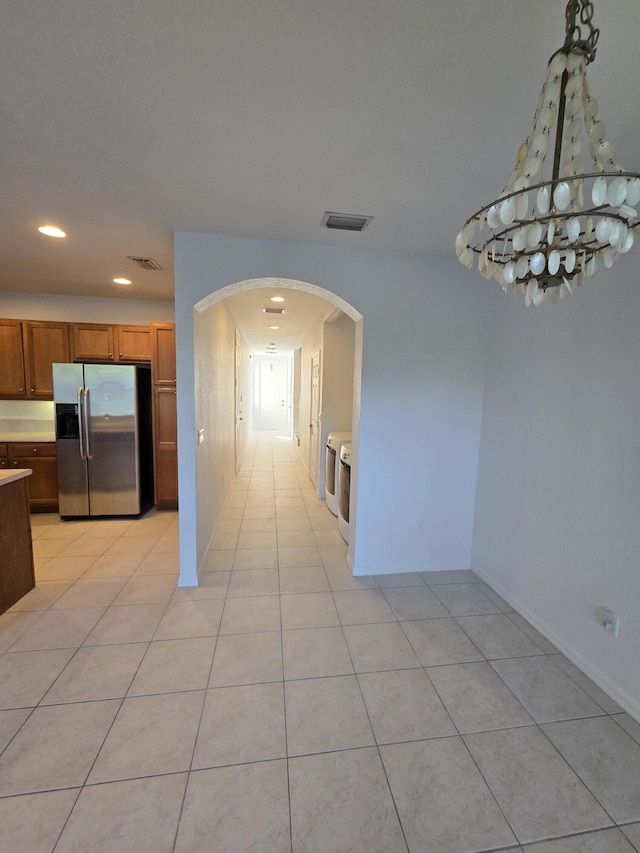 unfurnished dining area featuring arched walkways, visible vents, washer and clothes dryer, and light tile patterned floors