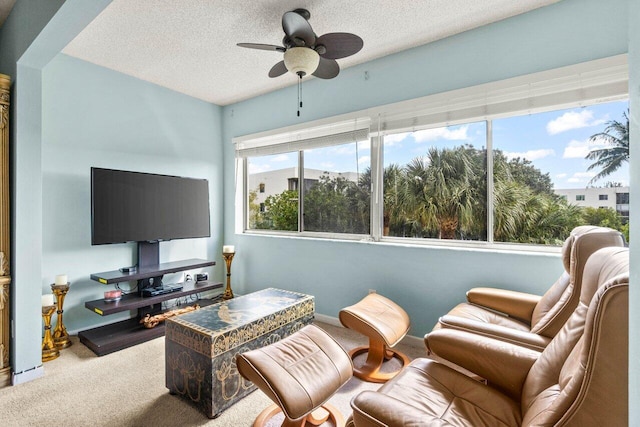 carpeted living room featuring ceiling fan and a textured ceiling