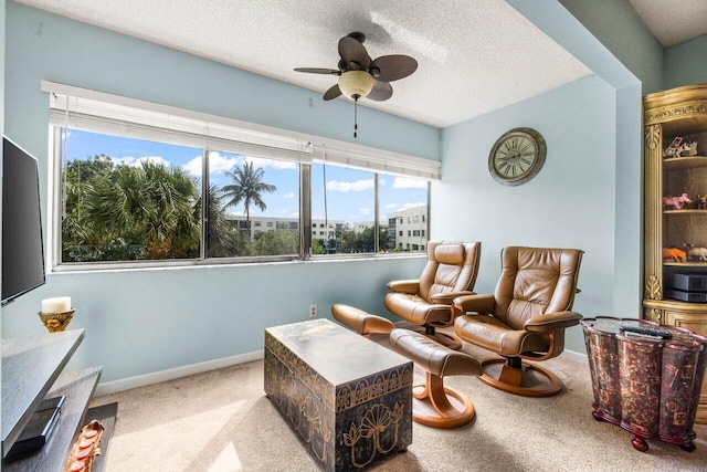 living area featuring ceiling fan, light colored carpet, and a textured ceiling