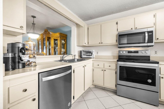 kitchen featuring hanging light fixtures, appliances with stainless steel finishes, sink, and cream cabinetry