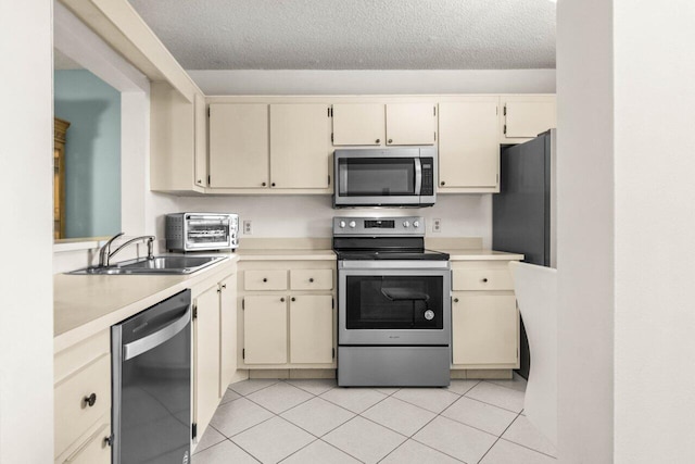 kitchen featuring cream cabinets, light tile patterned floors, sink, and appliances with stainless steel finishes