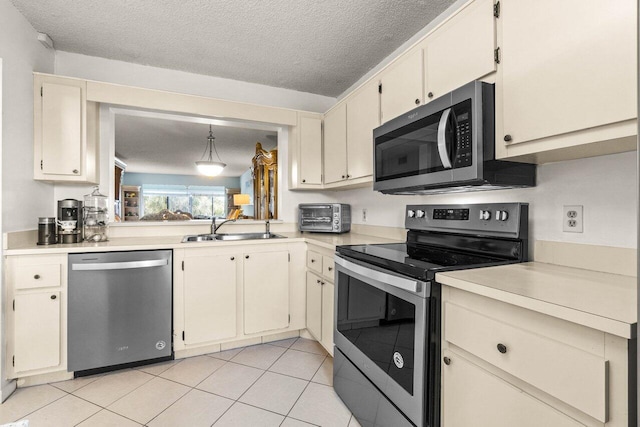 kitchen featuring stainless steel appliances, decorative light fixtures, sink, and a textured ceiling