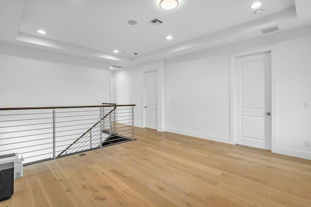 unfurnished room with a tray ceiling and light hardwood / wood-style floors