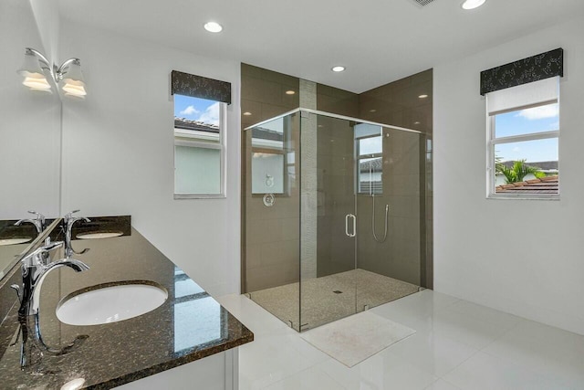 bathroom with a shower with door, vanity, and tile patterned floors