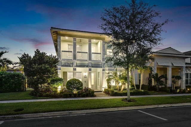 view of front of home with a balcony and a yard