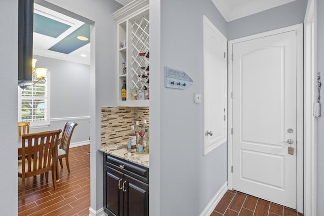 bar with light stone counters, ornamental molding, and decorative backsplash