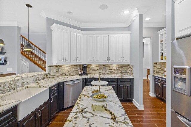 kitchen featuring sink, stainless steel appliances, light stone countertops, white cabinets, and decorative light fixtures