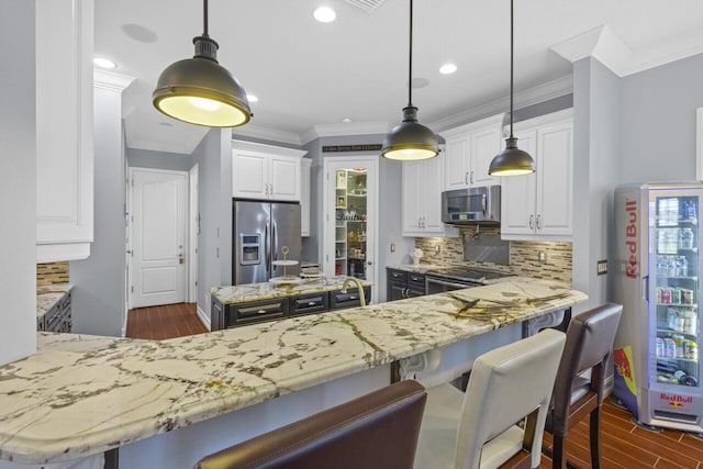 kitchen with hanging light fixtures, stainless steel appliances, kitchen peninsula, and white cabinets