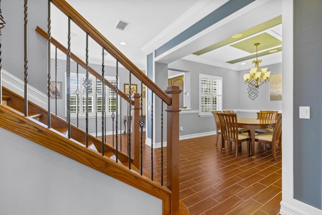 staircase featuring crown molding, a notable chandelier, and hardwood / wood-style flooring