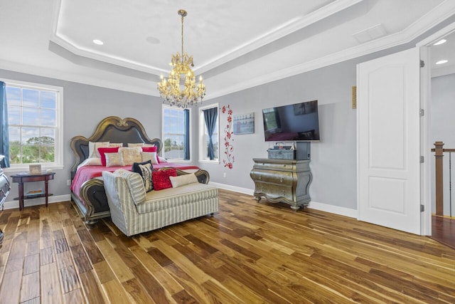 bedroom with ornamental molding, a tray ceiling, a chandelier, and hardwood / wood-style floors