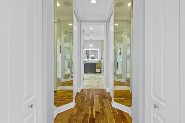 hall with sink, crown molding, and wood-type flooring