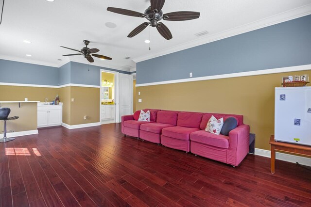 living room with crown molding, ceiling fan, and dark hardwood / wood-style flooring