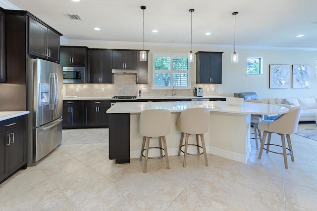 kitchen featuring appliances with stainless steel finishes, a kitchen island, a kitchen bar, and decorative light fixtures