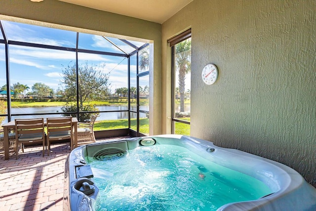 sunroom featuring a patio area, a water view, and a hot tub