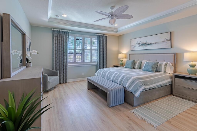 bedroom featuring light wood-type flooring, crown molding, and a raised ceiling