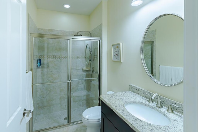 bathroom with vanity, toilet, and a shower with door