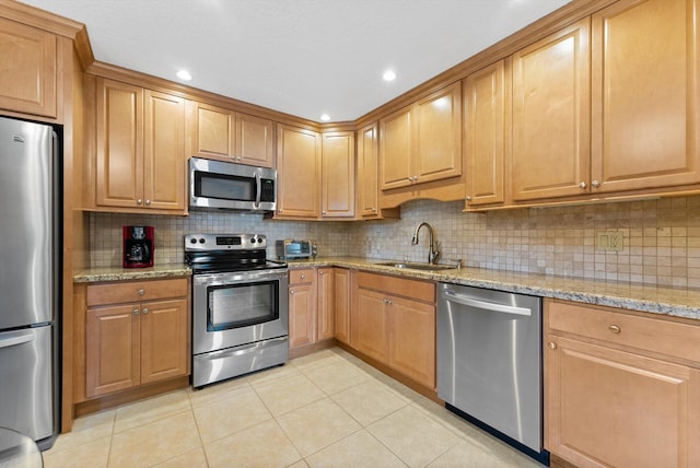 kitchen with light stone counters, appliances with stainless steel finishes, and sink