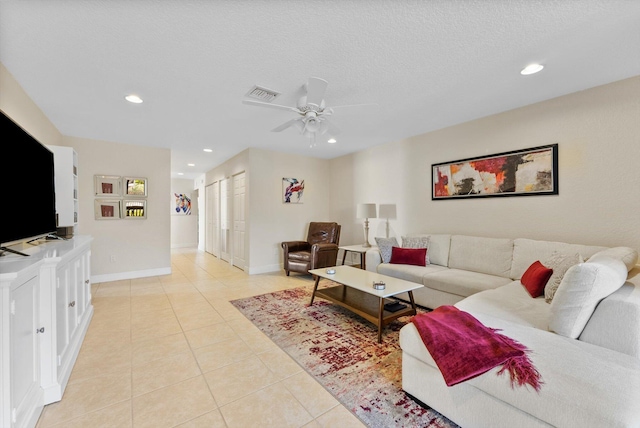 living room with a textured ceiling, ceiling fan, and light tile patterned flooring