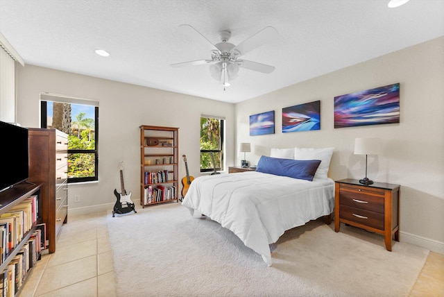 bedroom featuring multiple windows, light tile patterned flooring, a textured ceiling, and ceiling fan