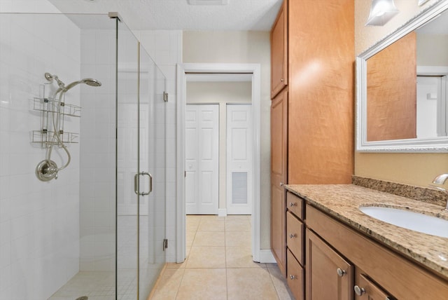 bathroom featuring tile patterned flooring, vanity, an enclosed shower, and a textured ceiling