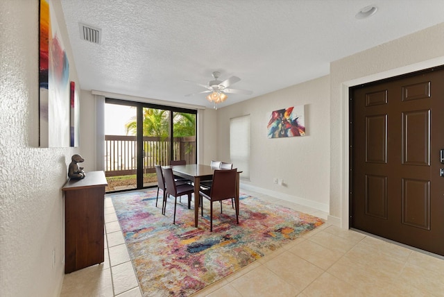 dining space featuring ceiling fan, light tile patterned floors, and a textured ceiling