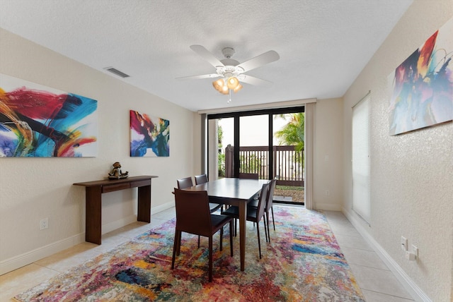 tiled dining space with ceiling fan and a textured ceiling