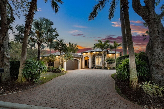 mediterranean / spanish-style house with a garage, decorative driveway, and stucco siding