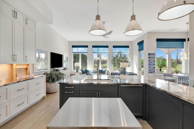 kitchen with hanging light fixtures, a kitchen island, sink, and white cabinets