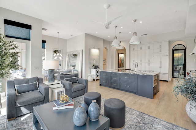 living room featuring sink, light hardwood / wood-style flooring, and ceiling fan