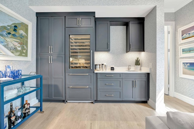 bar featuring crown molding, beverage cooler, light hardwood / wood-style flooring, and gray cabinetry