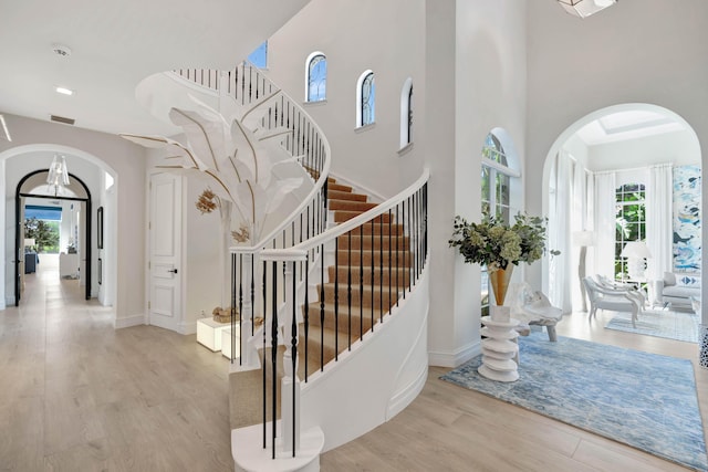 foyer entrance with a towering ceiling, a healthy amount of sunlight, and light wood-type flooring