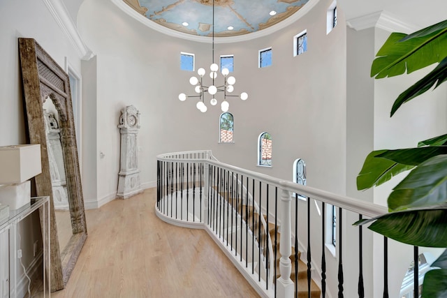 corridor with an inviting chandelier, ornamental molding, and light hardwood / wood-style floors