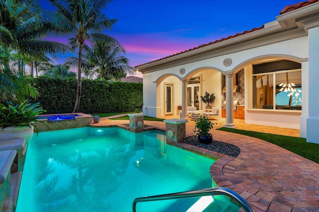 pool at dusk with an in ground hot tub, ceiling fan, and a patio