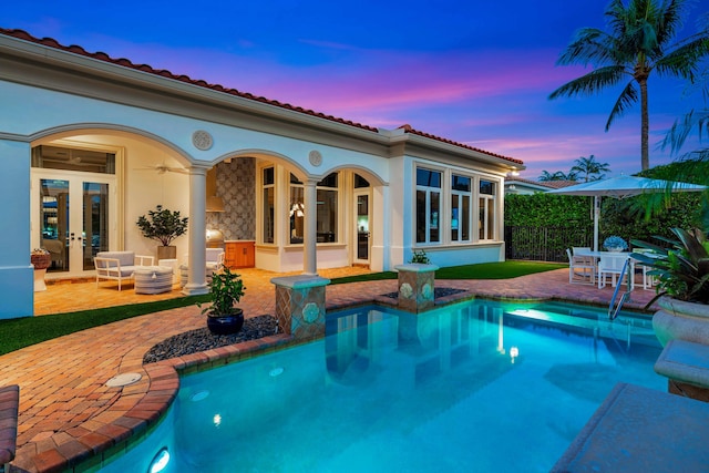 pool at dusk with a patio area, ceiling fan, and french doors