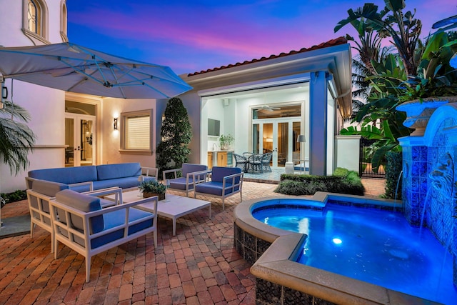 pool at dusk with french doors, outdoor lounge area, and a patio