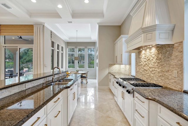 kitchen featuring sink, custom range hood, white cabinets, dark stone counters, and stainless steel gas stovetop