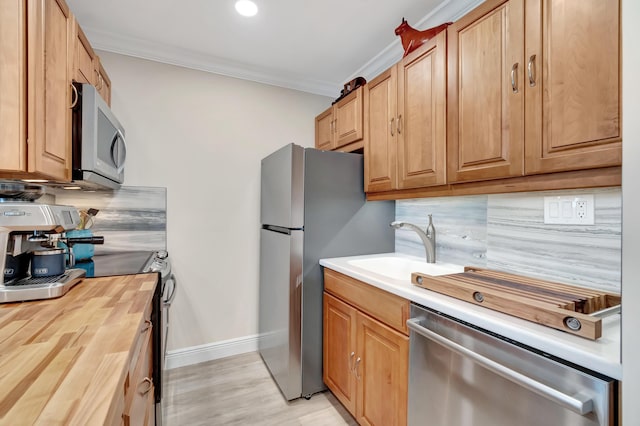 kitchen with crown molding, wood counters, appliances with stainless steel finishes, and decorative backsplash