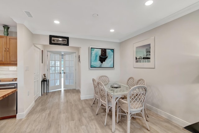 dining space with ornamental molding, light wood-type flooring, and french doors