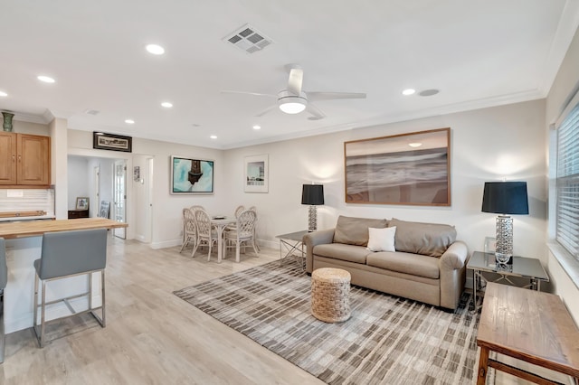 living room with crown molding, ceiling fan, and light hardwood / wood-style flooring