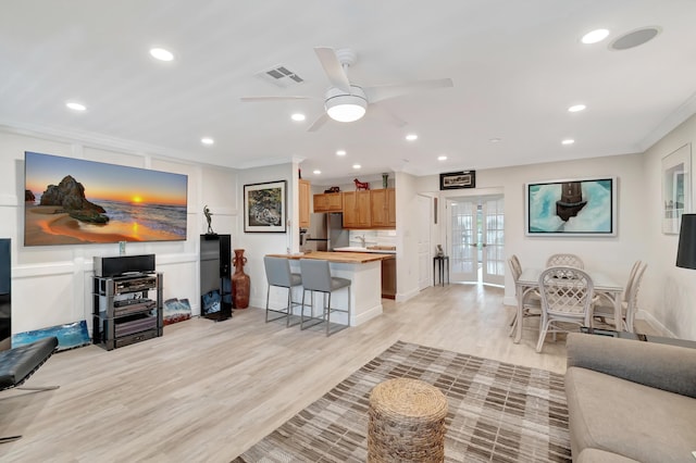 living room featuring ornamental molding, ceiling fan, light hardwood / wood-style floors, and french doors