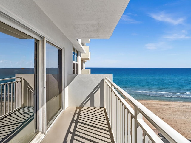 balcony with a water view and a view of the beach