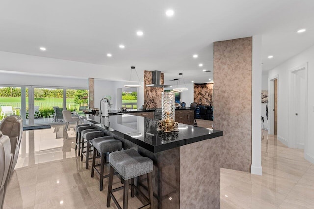 11955 N Lake Dr, Boynton Beach, FL 33436 - kitchen featuring pendant lighting, wall chimney exhaust hood, a kitchen breakfast bar, and kitchen peninsula