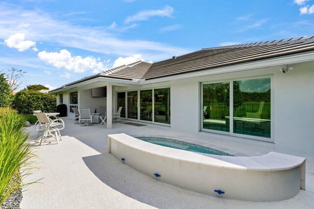 11955 N Lake Dr, Boynton Beach, FL 33436 - rear view of property with an outdoor hot tub and a patio