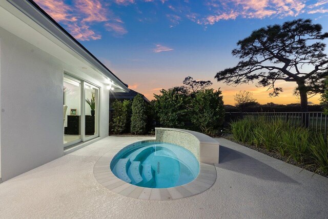 11955 N Lake Dr, Boynton Beach, FL 33436 - pool at dusk featuring a jacuzzi and a patio