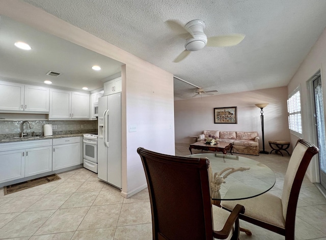 tiled dining area with sink, a textured ceiling, and ceiling fan