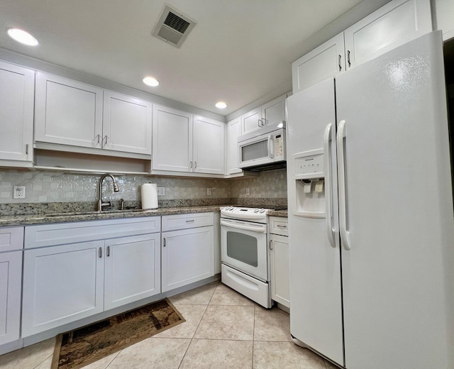 kitchen featuring tasteful backsplash, white cabinetry, sink, dark stone counters, and white appliances