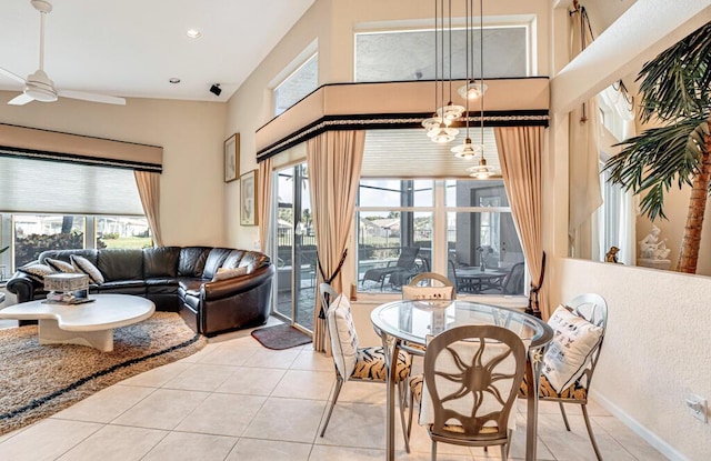 dining room with light tile patterned flooring, a towering ceiling, and ceiling fan