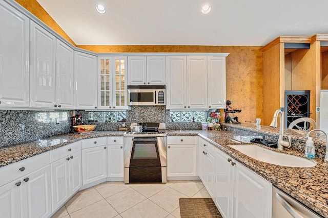 kitchen featuring sink, white cabinetry, light tile patterned floors, appliances with stainless steel finishes, and dark stone counters