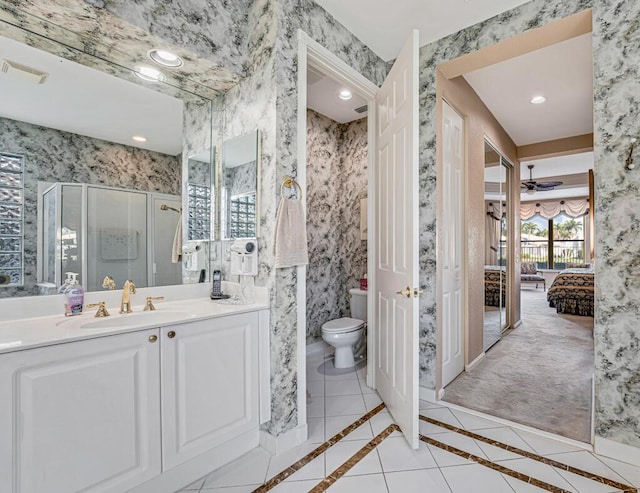 bathroom featuring ceiling fan, tile patterned flooring, vanity, a shower with shower door, and toilet