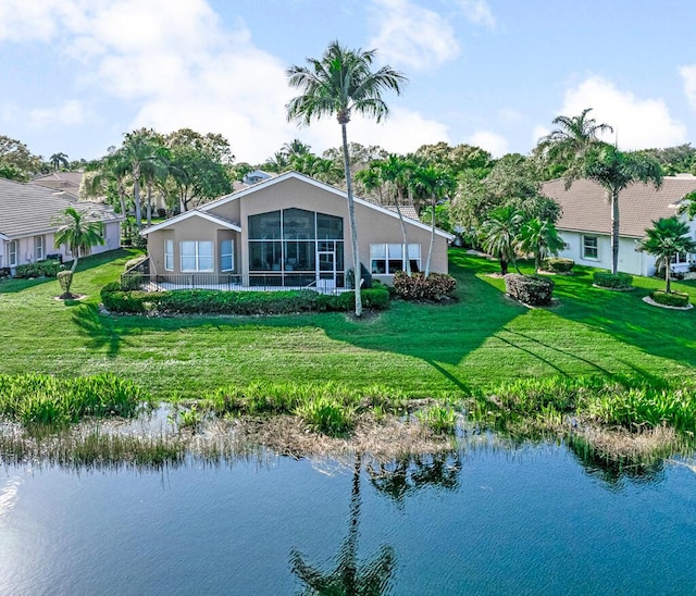 back of property featuring a water view and a lawn